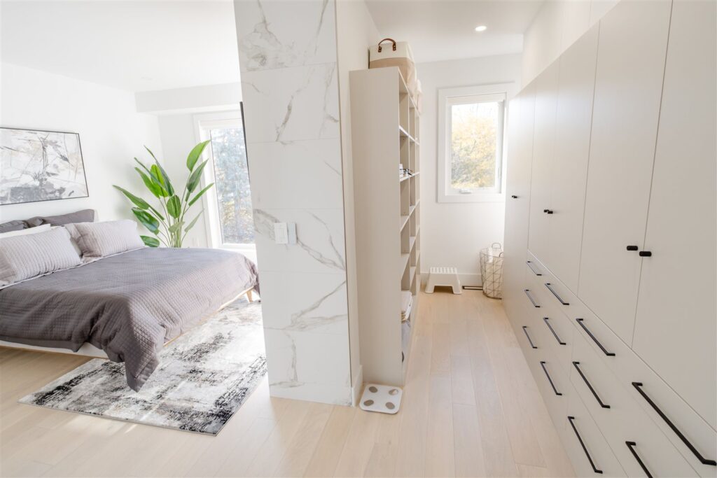Bright bedroom with grey bedding, a white marble accent wall, and natural light
