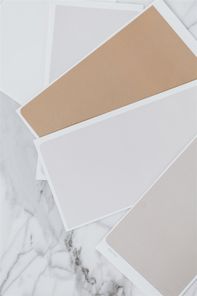 Beige, taupe, and grey paint swatches spread on a marble surface