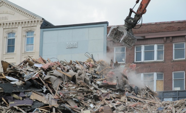 a-bulldozer-digging-through-a-pile-of-rubble-in-front-of-a-building