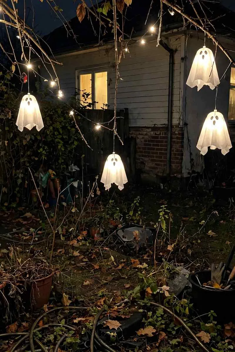 Ghost lights hanging from tree branches in a front garden at night