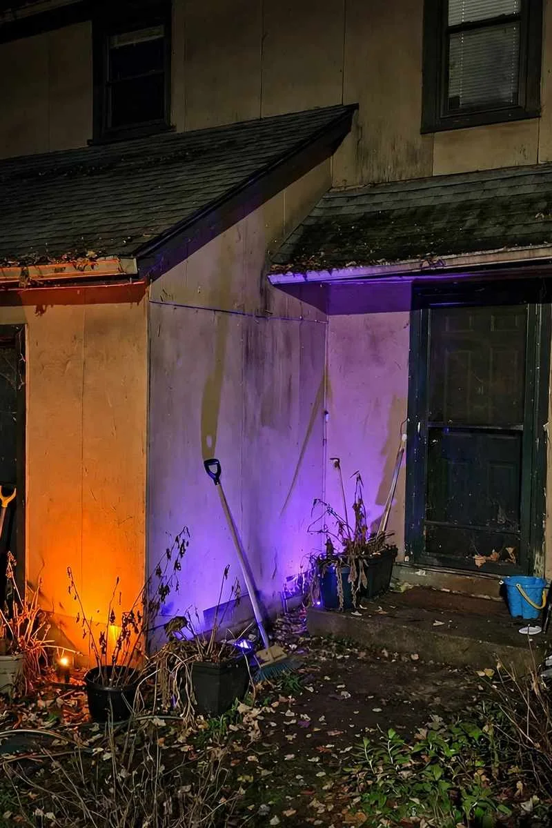 Orange and purple uplights washing the walls of a house at night