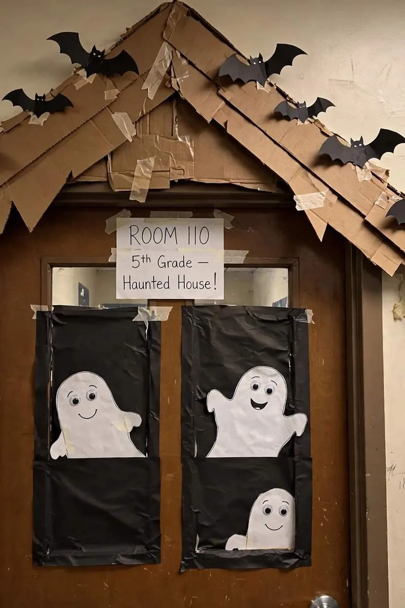 Haunted house classroom door with paper windows, pointed roof and friendly ghosts
