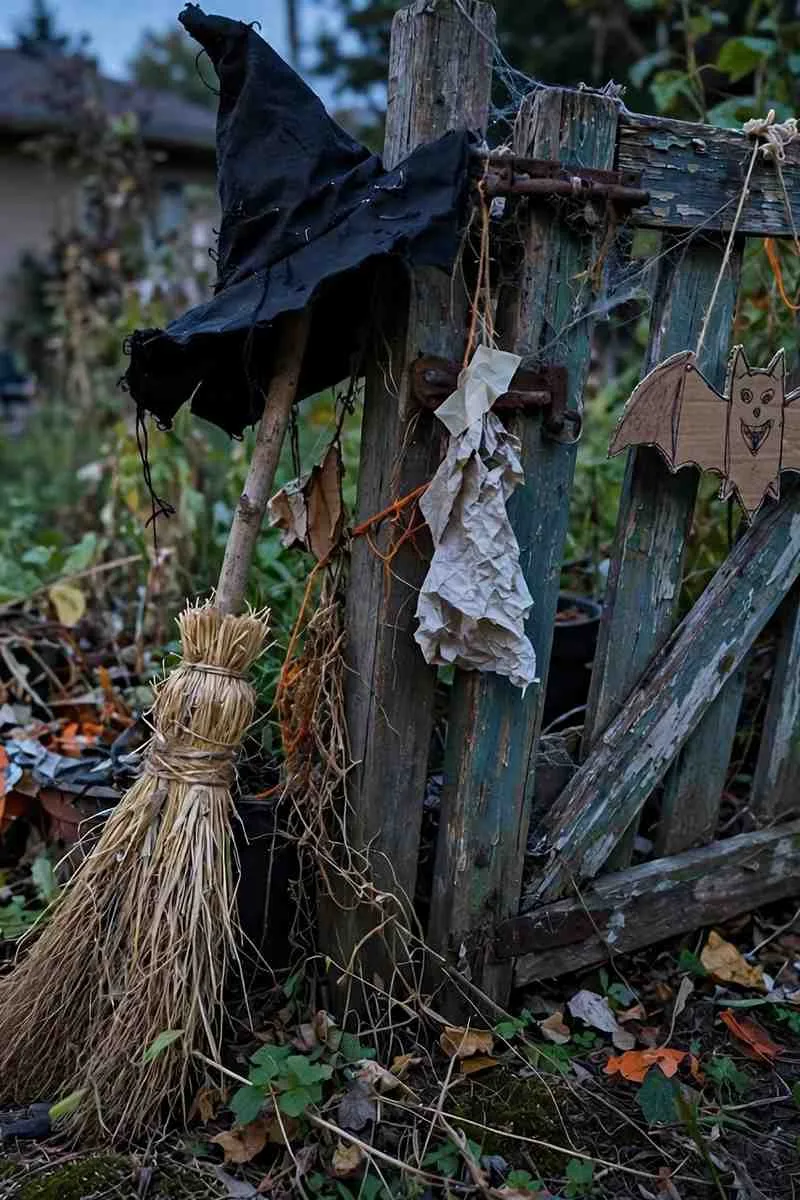 Witch's broom and hat leaning against a garden gate