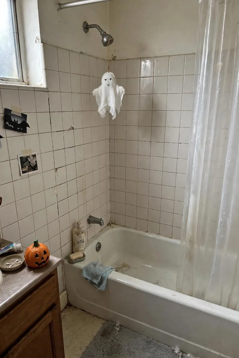 Small ghost decoration hanging from a shower head in a bathroom